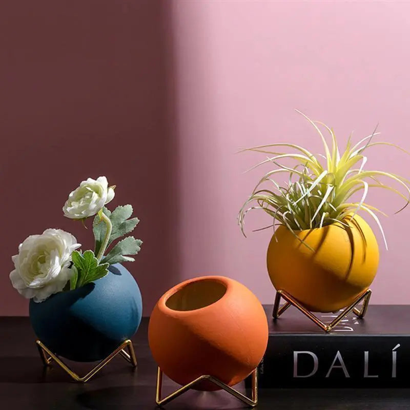 Macetas decorativas redondas con soportes metálicos geométricos