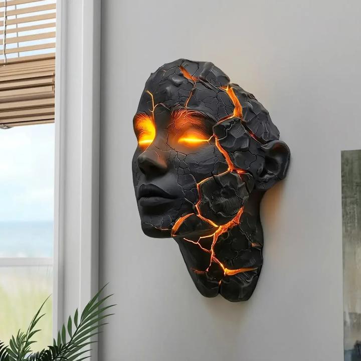 Skulptural LED-vägglampa med ansiktsmotiv och upplysta sprickor