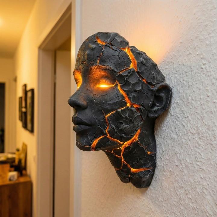 Skulptural LED-vägglampa med ansiktsmotiv och upplysta sprickor